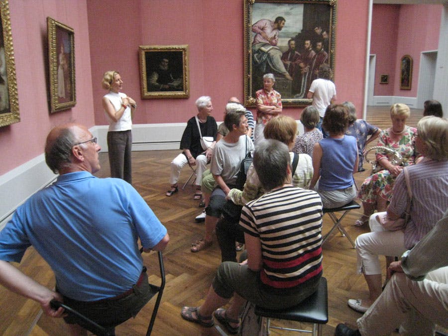 Eine sitzende Gruppe von Menschen betrachtet Gemälde in einer Galerie